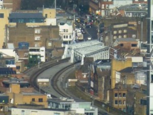 This is a telephoto view of what I'm fairly sure is the bridge that takes the new Overground line across the top of Shoreditch High Street. The buses are on the end of Kingsland Road near the Geffrye Museum. The line of shops features in a section of the novel connected with street art, although this piece might be one of the casualties of revision. I was trying to spot Village Underground, with its tube trains on the roof. It appears to be hidden from the top of the Shard by the Broadgate Tower -- see the extreme right edge of the photo.